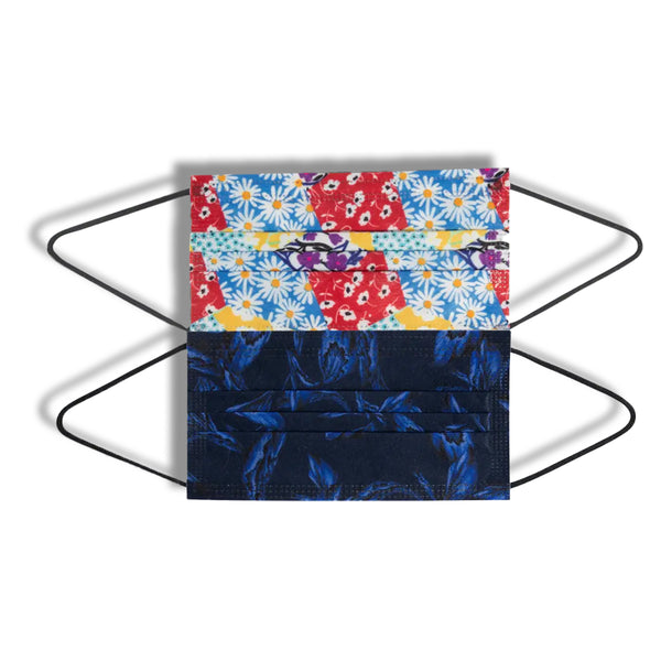 Two fabric face masks with ear loops placed on a light background. The top mask has a colorful floral patter with red, blue, and yellow daisies, while the bottom mask features a dark blue floral design. Both masks are positioned diagonally.