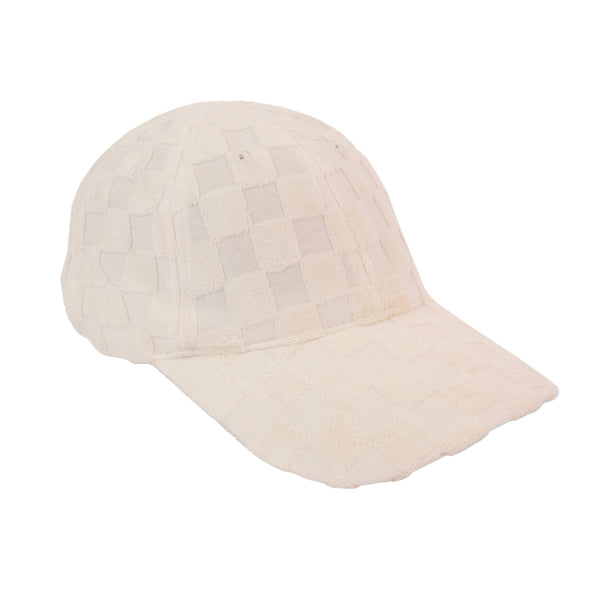 A light-colored baseball cap with a checkered pattern and visible stitching along the seams. The cap has a curved brim and is made of a soft material, displayed against a white background. 